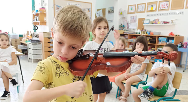 ילד מנגן בכינור בפני ילדים אחרים בגן